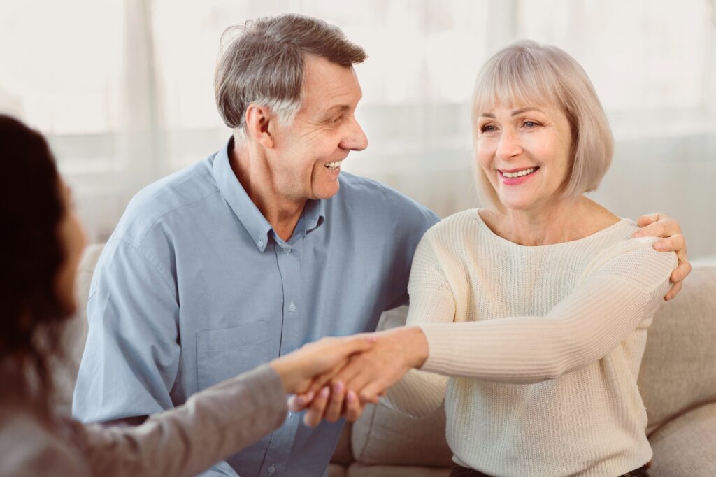 Happy elderly couple giving female doctor handshake